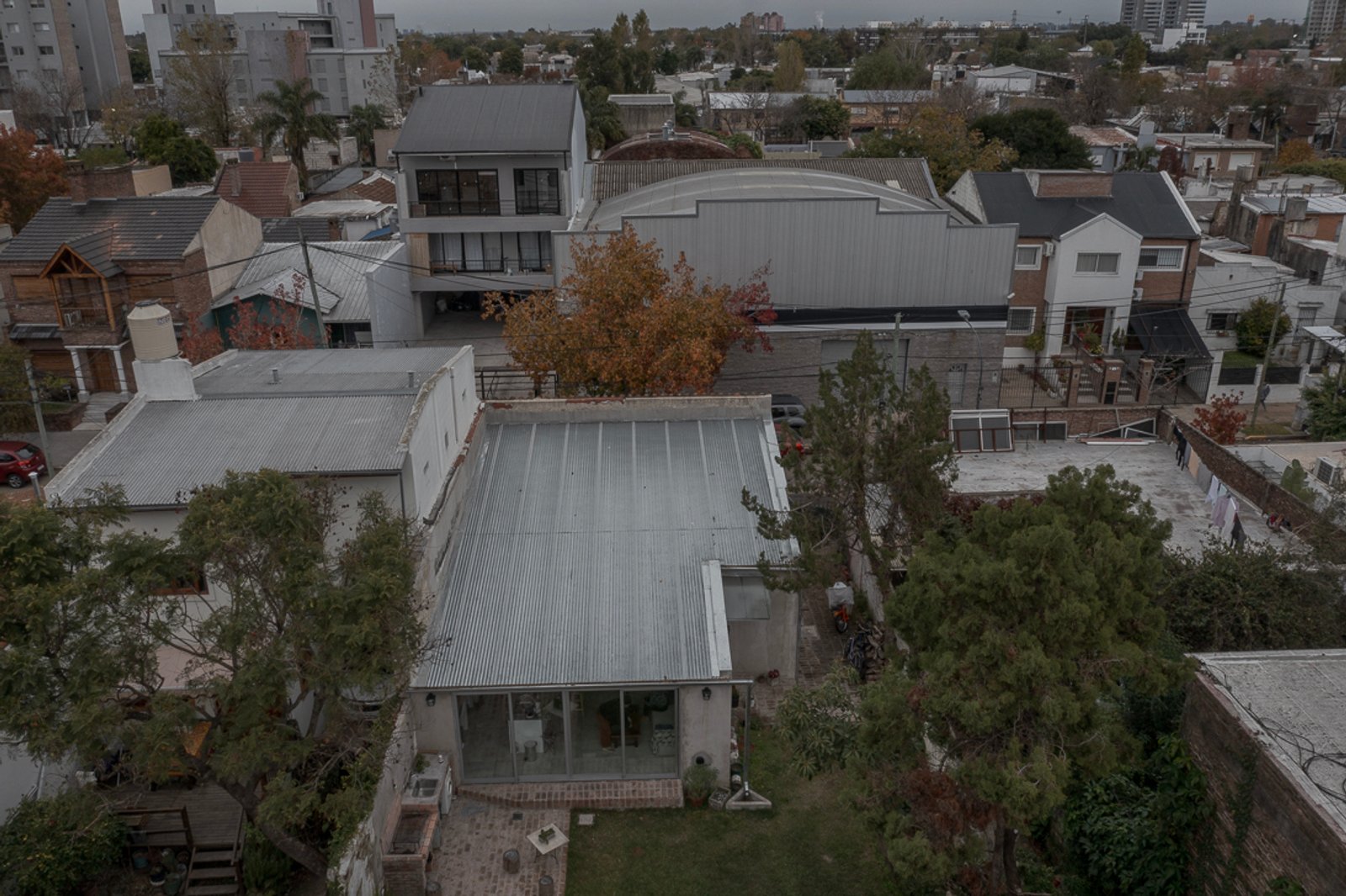Edifício residencial moderno de concreto branco com telhado de metal — projeto Reforma Navarro, por Estudio YME, em B1648 Tigre